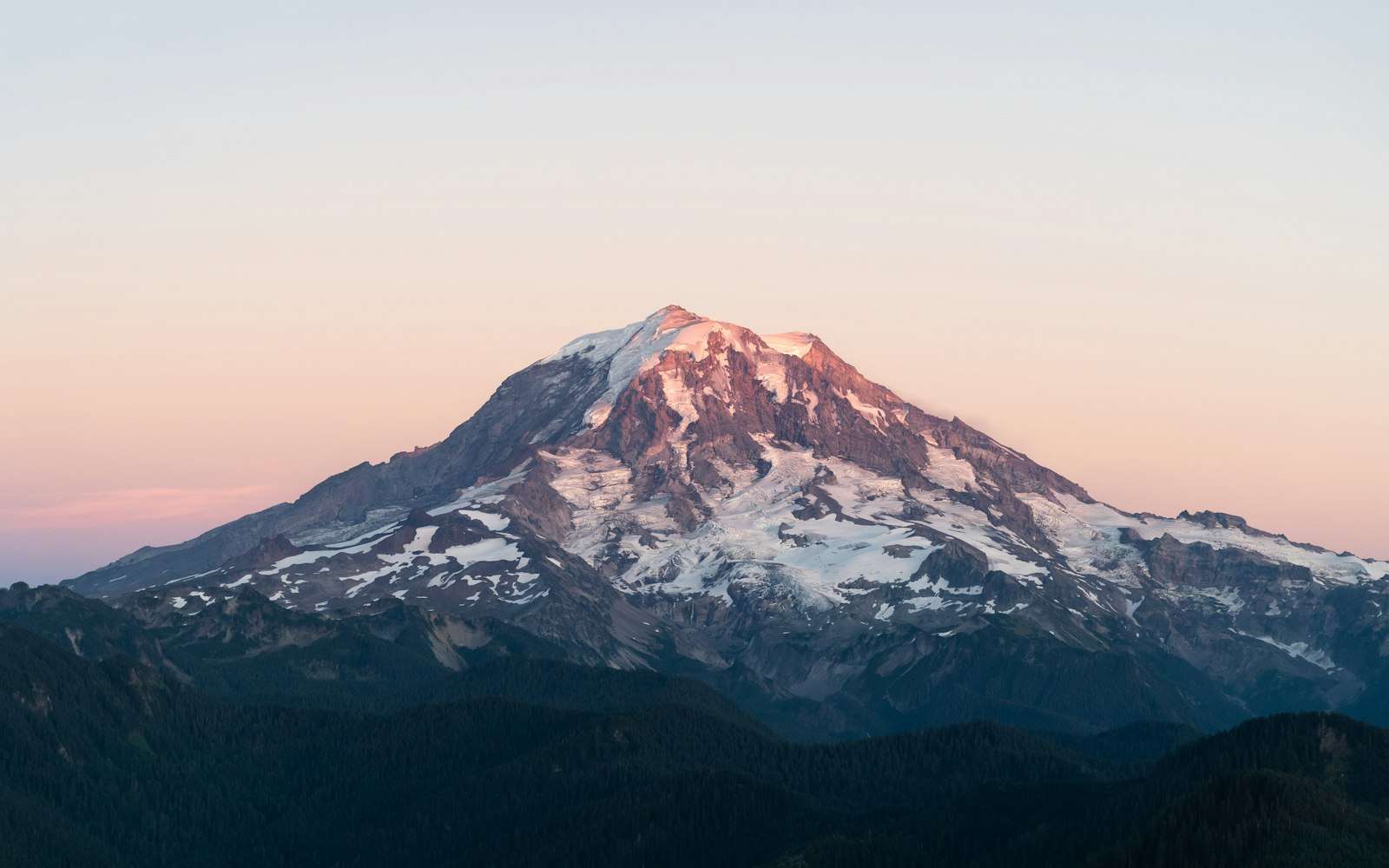Mount Rainier at dusk above the forest ridges